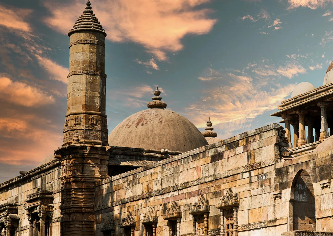 The magnificent sandstone dome and minaret of the Jama Masjid in Ahmedabad, set against a dramatic and colorful sunset sky