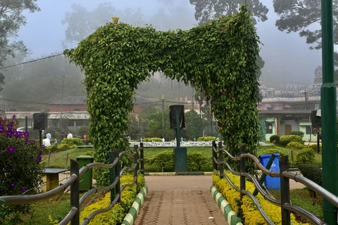 The lush, vine-covered entrance archway to the misty gardens of Raja's Seat, a popular tourist viewpoint in Madikeri