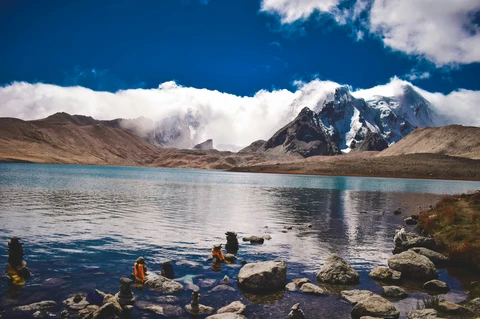 The pristine turquoise waters of the high-altitude Gurudongmar Lake, with snow-capped Himalayan peaks rising behind it in Sikkim