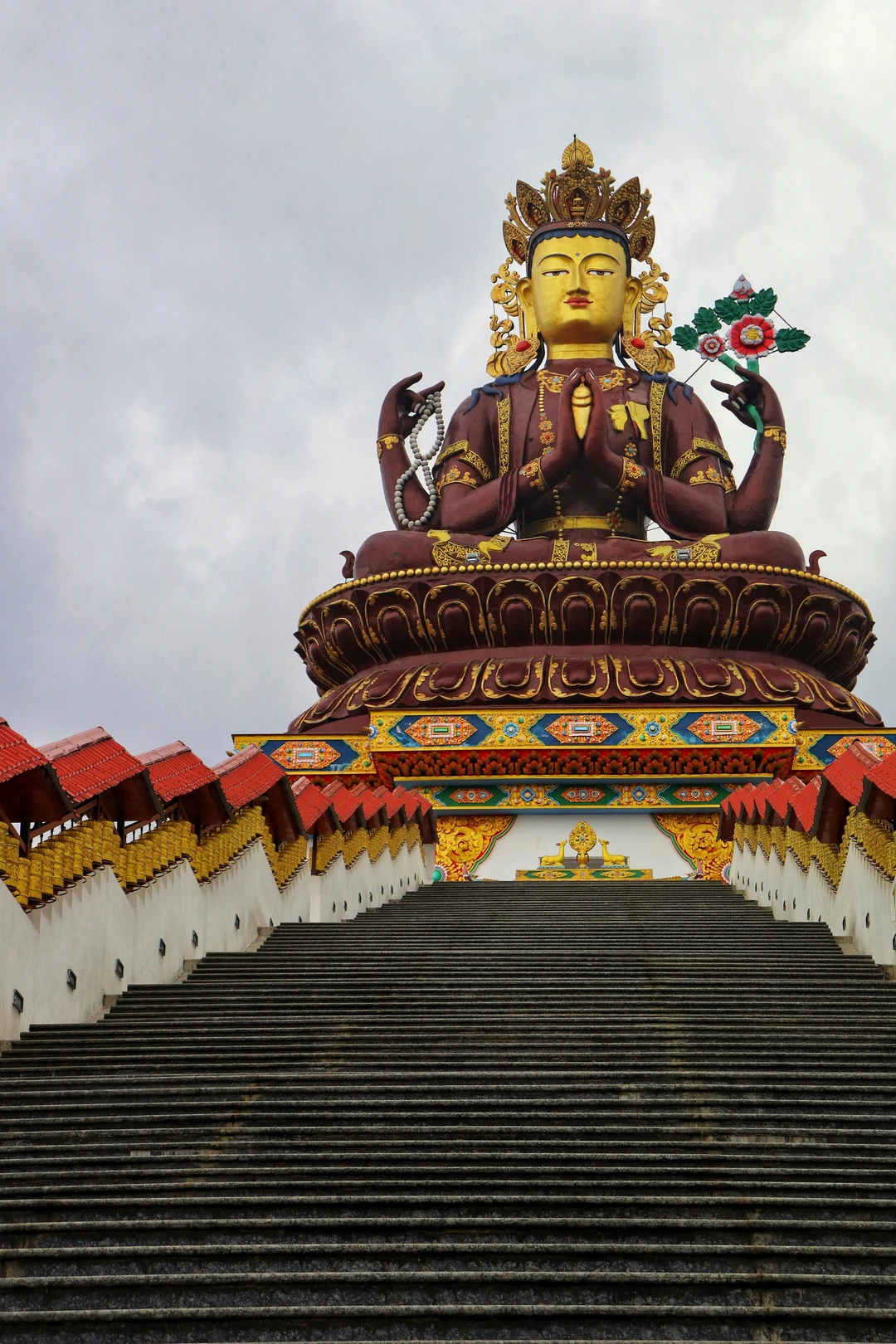 A view looking up a long staircase towards the massive, ornate statue of Chenrezig at the Siddheshwar Dham pilgrimage complex