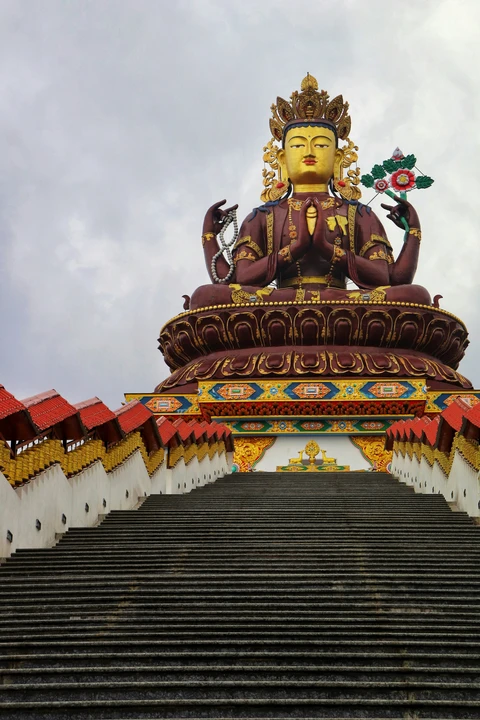 A view looking up a long staircase towards the massive, ornate statue of Chenrezig at the Siddheshwar Dham pilgrimage complex