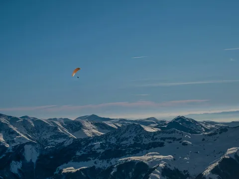 Snow on the Military Road: Gudauri Winter Escape | Safari Sutra Holidays Tandem paraglider over snowy Gudauri slopes on a Georgia winter tour package from India