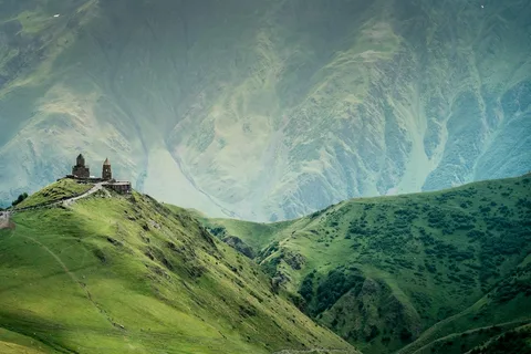 Mountains, Monasteries & a City of Love: Georgia Honeymoon | Safari Sutra Holidays Gergeti Trinity Church below snowy Mount Kazbek on a Georgia honeymoon package from India