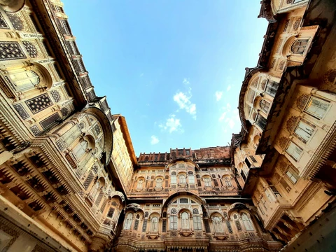 The Intricate Courtyards of Mehrangarh Fort, Jodhpur A low-angle view looking up from a courtyard at the intricately carved sandstone balconies and jali screens of Mehrangarh Fort