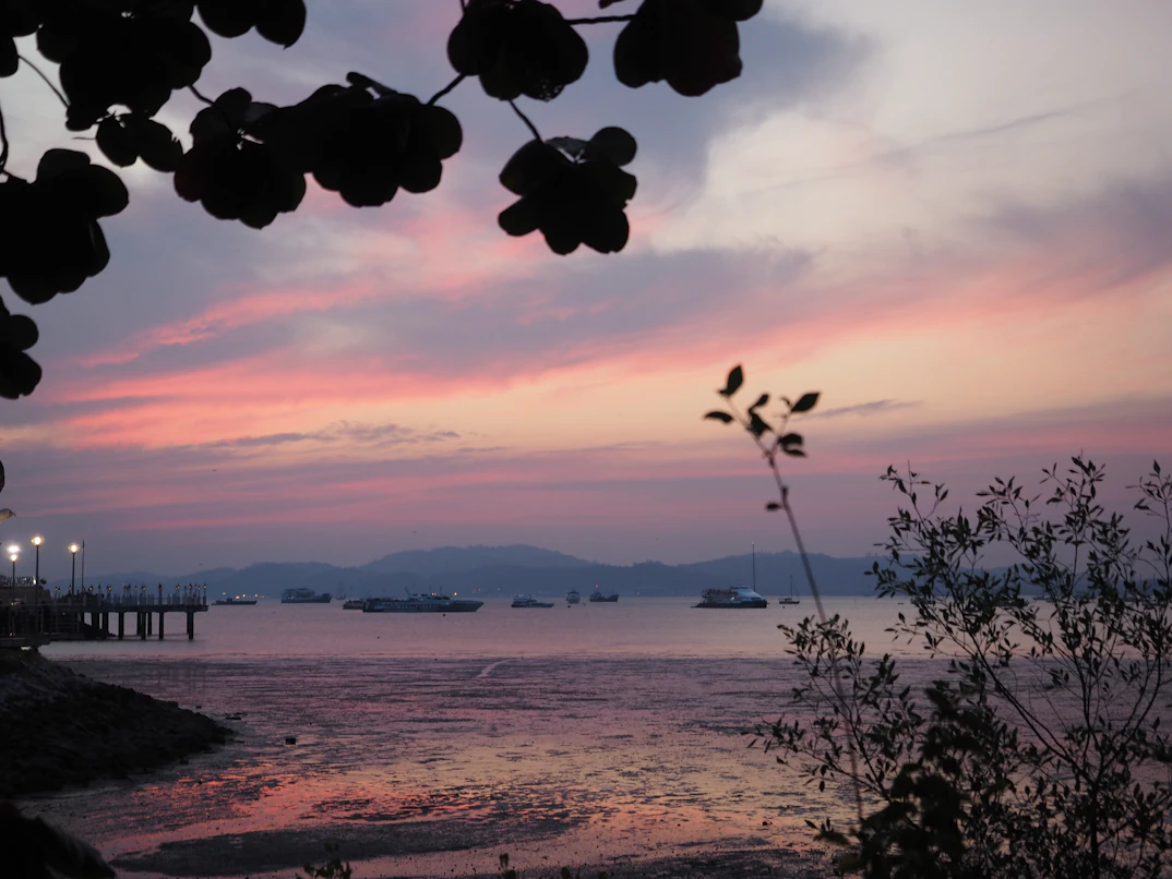 Langkawi beach with turquoise water and jungle hills at sunset — Malaysia honeymoon package from India
