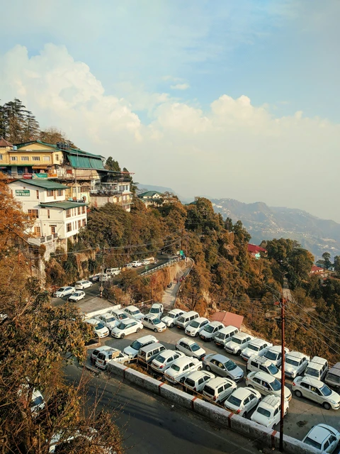 A bustling taxi stand in Mussoorie, with cars parked below the hotels and shops built along the steep Himalayan foothills