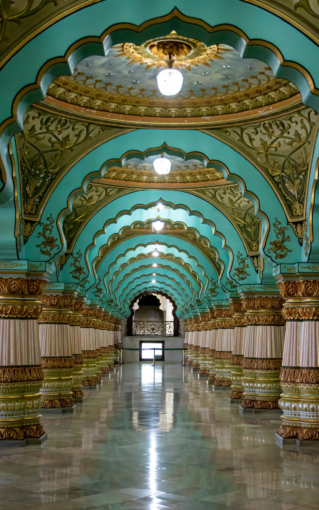 The magnificent corridor of the Mysore Palace, featuring its famous ornate pillars and turquoise scalloped arches