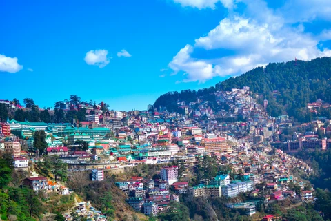 Shimla: Scenic View of the Queen of Hills The vibrant cityscape of Shimla, with colorful houses and hotels covering the lush Himalayan hillside under a bright blue sky.
