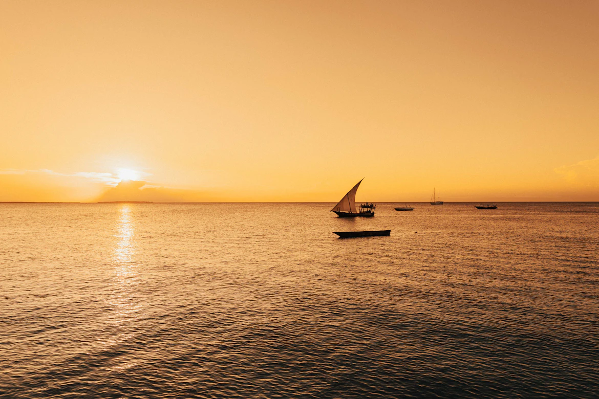 Traditional dhow sailing on Zanzibar's turquoise water at sunset — Tanzania honeymoon safari package from India
