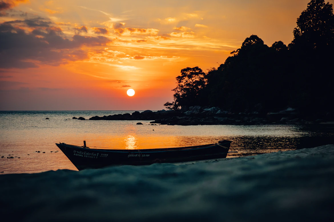 Traditional junk boat sailing through Ha Long Bay limestone karsts at sunrise — Vietnam honeymoon package from India