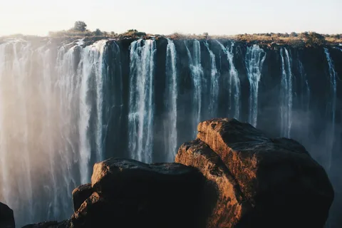 The Smoke That Thunders: Victoria Falls Family Holiday | Safari Sutra Holidays Victoria Falls with a rainbow in the spray on a Victoria Falls family tour package from India