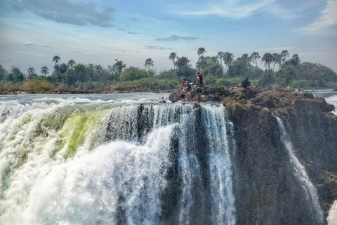 Rapids, Rock Pools & Wild Kafue: Zambia Adventure | Safari Sutra Holidays Swimmer at Devil's Pool on the edge of Victoria Falls on a Zambia adventure tour package